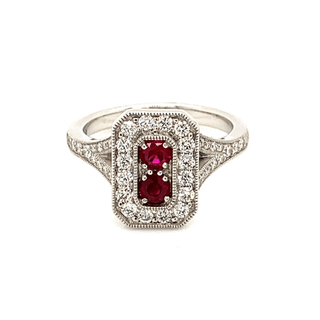 A platinum ring featuring a central square-shaped ruby surrounded by a halo of round-cut diamonds, with additional diamonds set along the ring's shoulders.