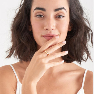 Woman with a gold twisted ring on her finger against a white background