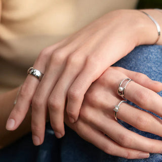 Close-up of hands with silver rings on a blurred background
