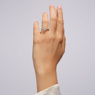 Hand wearing a diamond ring on a plain background