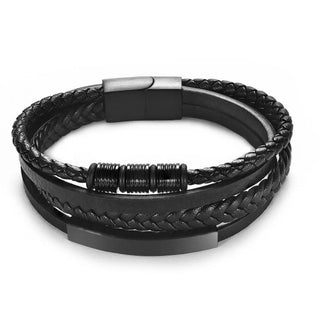 Black multi-strand leather bracelet with braided and smooth woven bands, a polished metal clasp, and a textured spacer, shown on a white background.