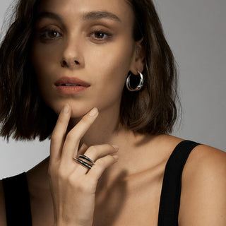 Woman with shaun leane hoop earrings and rings on a neutral background