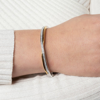 Close-up of a wrist wearing two silver bracelets on a white background