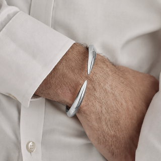 Silver bangle on a person wearing a light-colored shirt.