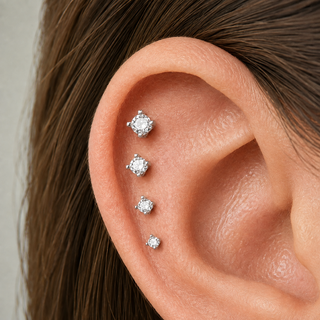 A close-up of a person's ear showcasing a four-stud ear cuff set made of silver-toned metal and clear gemstones, with the hair on the side of the head visible.