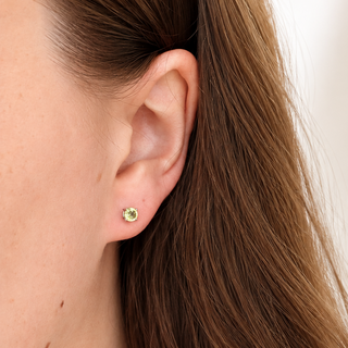Close-up of an ear wearing a small earring with a blurred background
