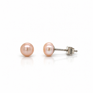 A pair of round light pink freshwater pearl stud earrings with silver posts and butterfly backings, displayed on a clean white background with a soft reflection.