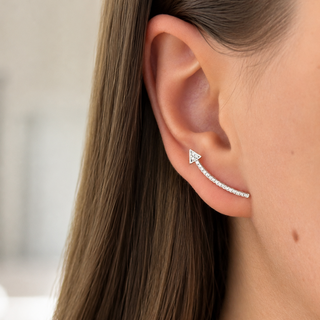 Close-up of an ear wearing a silver earring with a blurred background