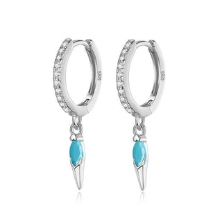 A pair of turquoise and clear stone spike drop huggies with silver hoops and rhodium plating.