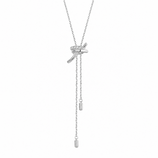 A silver-toned lariat-style necklace with a bow-shaped pendant set with small clear stones, featuring two dangling chain tails ending in cylindrical charms, shown on a plain white background.