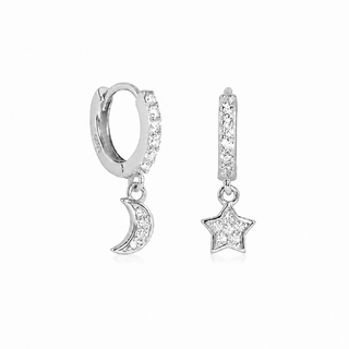A pair of silver huggie hoop earrings, one featuring a dangling crescent moon and the other a dangling star, both adorned with clear pavé stones, set against a plain white background.