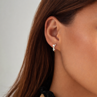 Close-up of an ear wearing a star-shaped earring with a neutral background