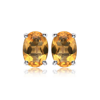A pair of silver oval citrine stud earrings with butterfly back closures, set against a white background.