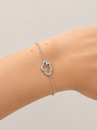 Silver bracelet with a heart-shaped clasp on a wrist against a neutral background