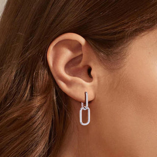 Silver earring worn by a person with brown hair