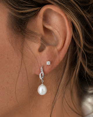 Close-up of an ear wearing a pearl earring with a blurred background