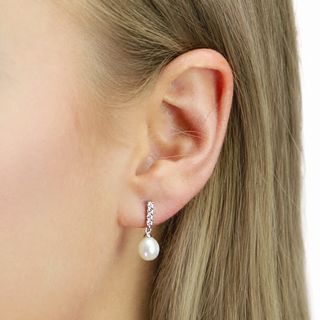Pearl earring worn by a person with blonde hair on a white background