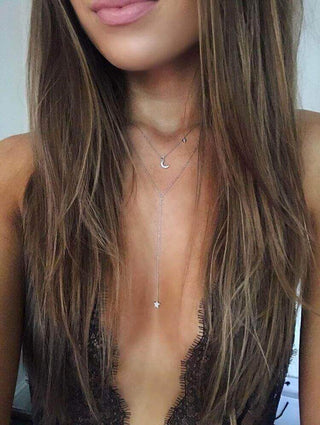 Close-up of a person wearing a delicate necklace with a star pendant.