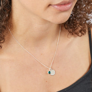 Close-up of a necklace with two pendants on a person wearing a black top.