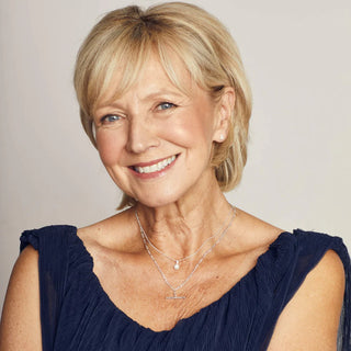 Woman with short blonde hair wearing a navy blue top against a plain background