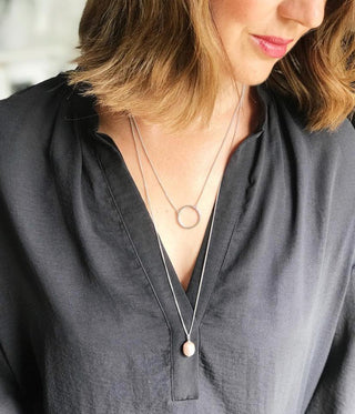 Person wearing a black shirt and a necklace with circular pendants.