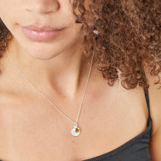 Close-up of a person wearing a silver necklace with a pendant.