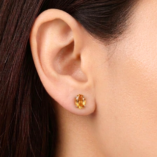 Close-up of an ear wearing a gold earring with a gemstone.