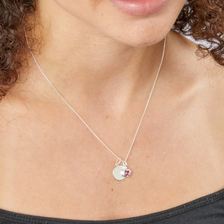 Silver necklace with a round pendant worn by a person