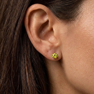 Close-up of an ear wearing a silver peridot stud earring with dark hair.