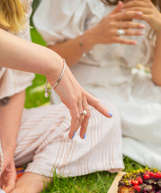 Close-up of hands with rings on a grassy surface