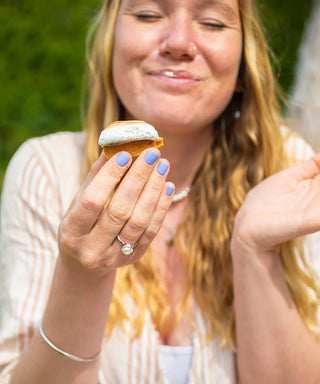 Woman holding a pastry outdoors with a blurred green background