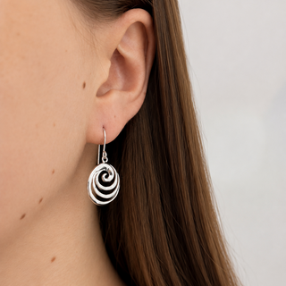 Silver spiral earring worn by a person with a neutral background