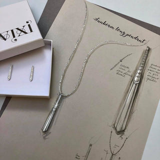 Silver necklace and earrings on a display card with 'Vivi' branding.