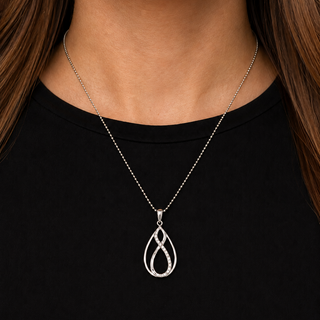 Silver necklace with a pendant worn by a person against a black background