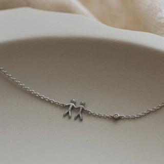 Silver bracelet with small figures on a beige surface