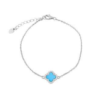 A delicate silver chain bracelet featuring a central turquoise-colored clover motif surrounded by small clear stones, with an adjustable clasp and heart-shaped tag on a light gray background.