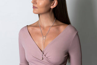 Woman wearing a long necklace with a plain background