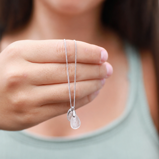 Necklace with a clear teardrop pendant held by a person