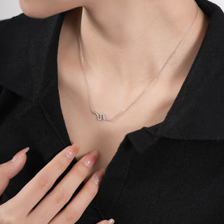 Necklace with a small snake pendant worn by a person against a neutral background