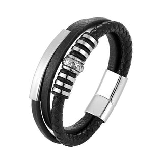 A men's multi-strand bracelet featuring black leather bands, one braided wrap, and polished silver-tone metal plates and a striped spacer, shown on a white background.