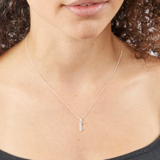 Silver necklace with a F shaped pendant worn by a person