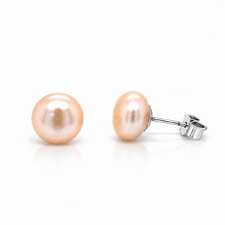 A pair of freshwater pearl stud earrings with a light peach-pink luster and silver post backs, shown on a clean white background.