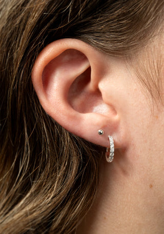 Close-up of an ear wearing a diamond hoop earring.
