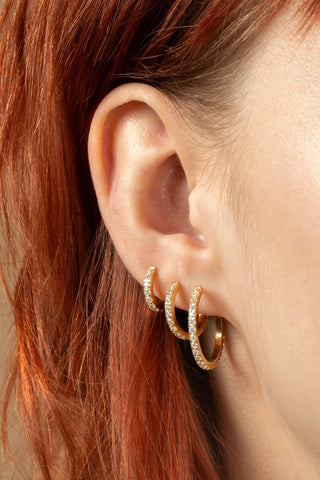 Gold hoop earrings worn by a person with red hair.