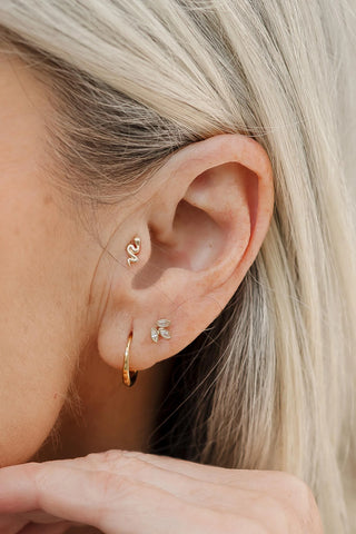 Close-up of an ear wearing gold hoop earrings with a blurred background