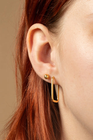 woman wearing gold earrings on  a beige background