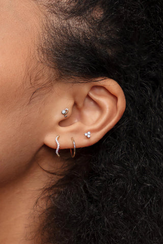 Close-up of an ear with multiple earrings on a dark background