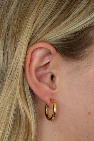 Gold hoop earring worn by a person with blonde hair.