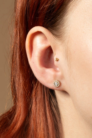 Close-up of an ear wearing two earrings with red hair.