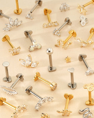 Collection of gold and silver earrings on a beige background